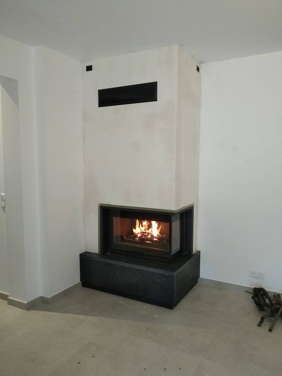 cheminée avec soubassement en marbre noir et insert en fonte à vitre latérale à Saint Etienne du Grès